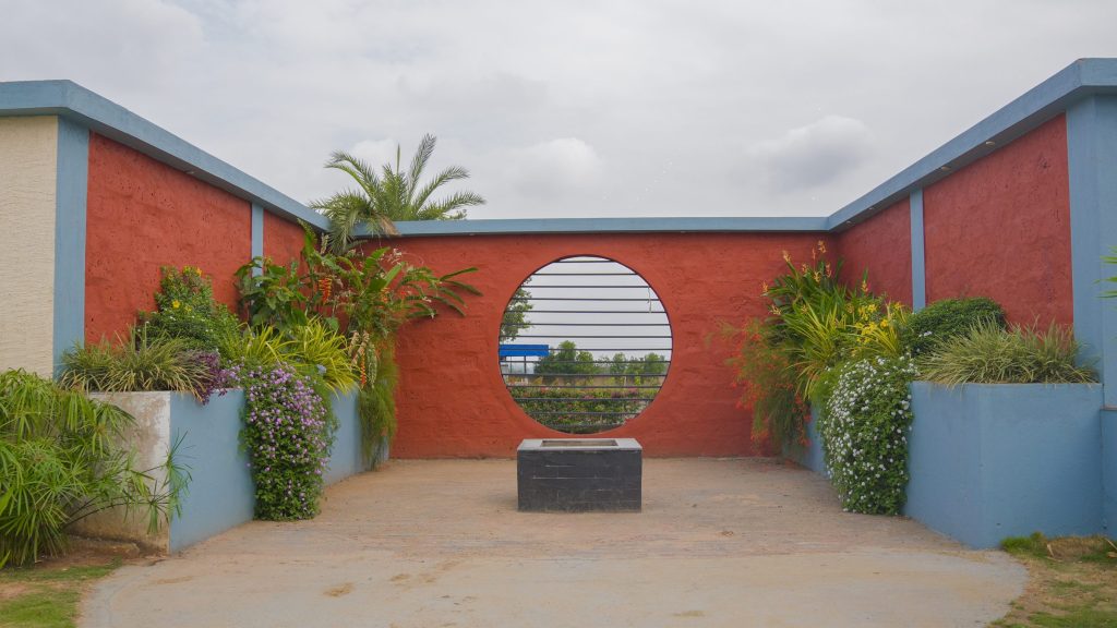 Courtyard with a red wall and a circular opening framed by plants