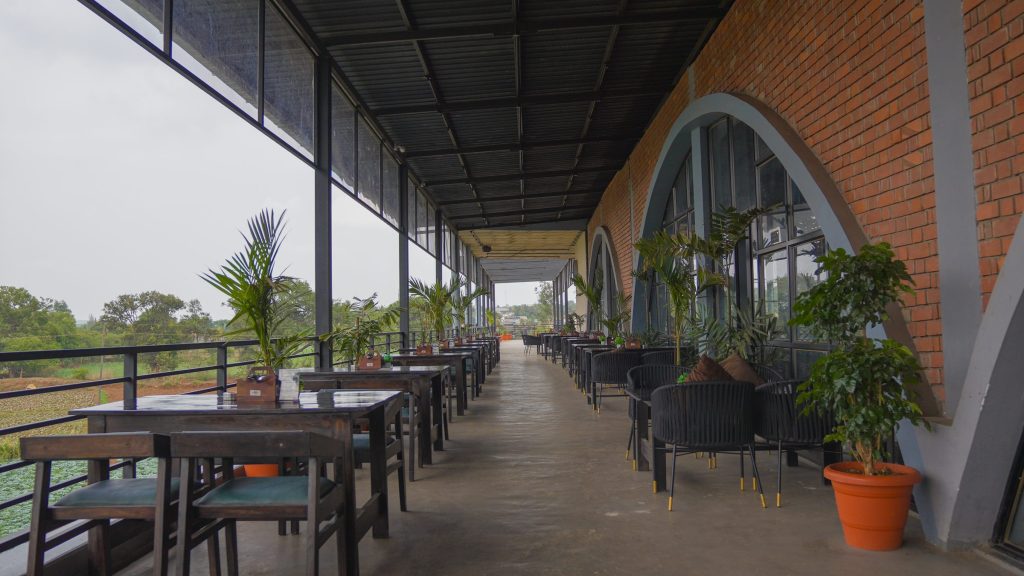 Long covered terrace with dining tables overlooking greenery